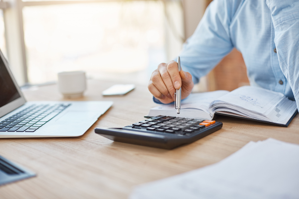 Businessman calculating licensing costs with a calculator and documents, representing the financial planning needed for permits.